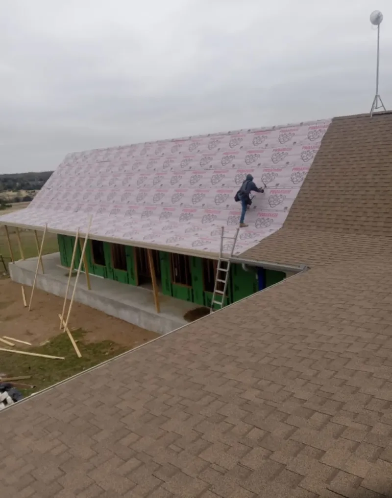 Worker preparing underlayment for a metal roof installation in Fruitville